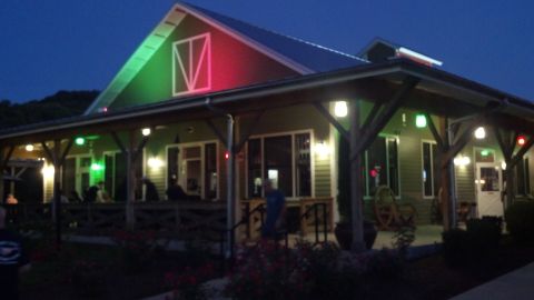 2007 Ford Mustang - A building with a covered porch is illuminated by red and green lights as dusk settles.
