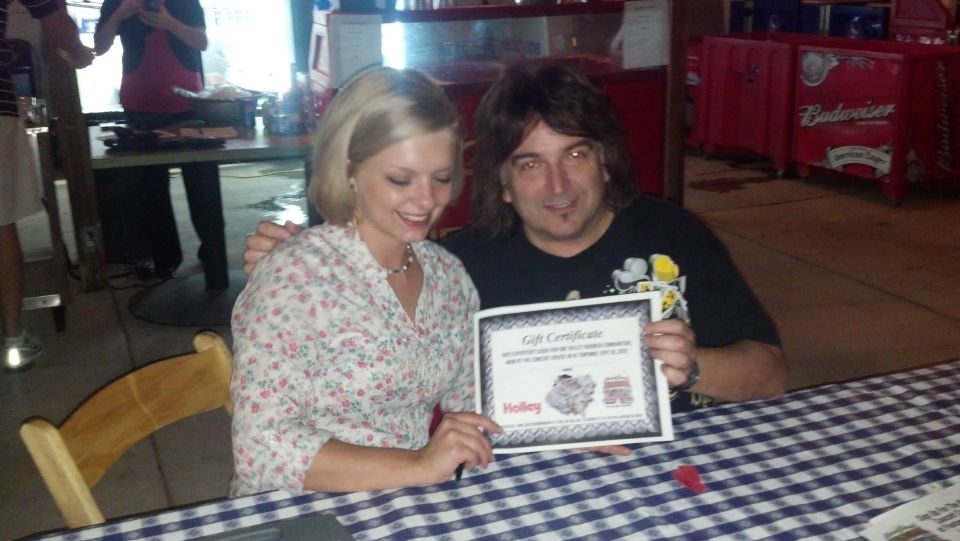 Two people posing with a Holley gift certificate at an event