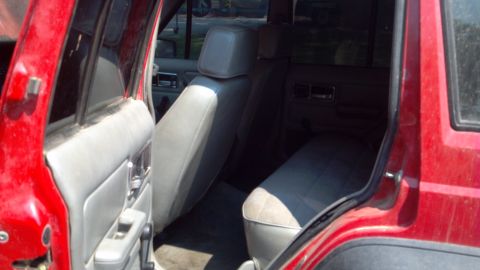 1995 Jeep Cherokee - The interior of a red Jeep Cherokee shows the rear seats and door trim.