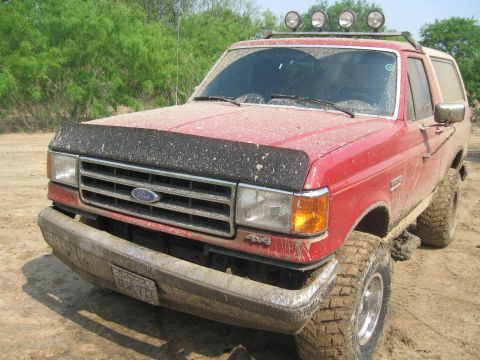 1990 Ford Bronco - This red 1990 Ford Bronco is covered in mud, suggesting it has been used for off-roading.