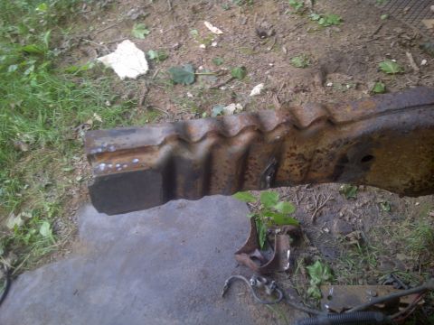 1995 Ford Bronco - Close-up of a damaged, rusted metal frame piece lying on the ground.
