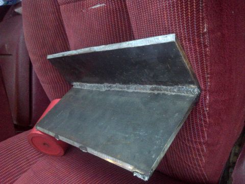 1995 Ford Bronco - A custom metal bracket is placed on a vehicle's seat, with a red object visible underneath.