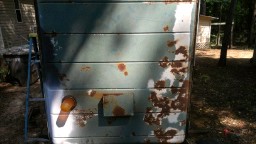 1978 Ford Bronco - Close-up of a heavily rusted metal panel, possibly from a storage unit or old equipment.