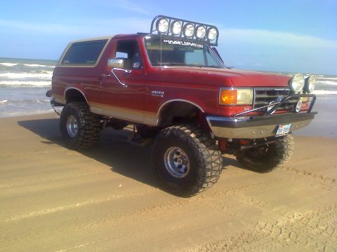 1990 Ford Bronco - This modified Ford Bronco sits on a beach, its off-road capabilities evident.