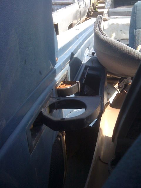 1979 Ford Bronco - Interior view of a vehicle with a damaged cup holder and blue trim, with other vehicles in the background.