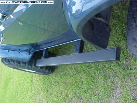 1992 Ford Bronco - Close-up view of a blue SUV's side step and tire on a grassy surface.