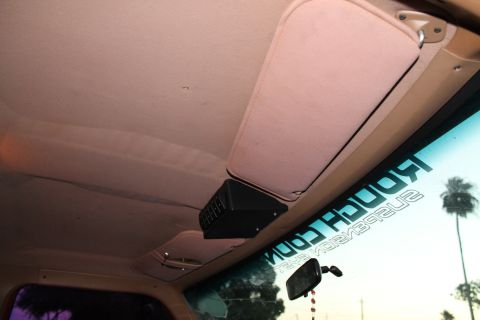 1990 Ford Bronco - The interior of a vehicle is shown, a sun visor and an overhead accessory, with a "Rough Country Suspension" sticker on the windshield.