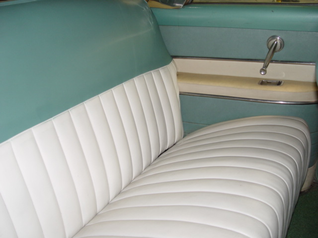 Classic car interior with white pleated bench seat and teal door panel