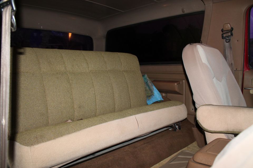 Rear bench seat and passenger seat inside a vehicle. A blue pillow is on the bench