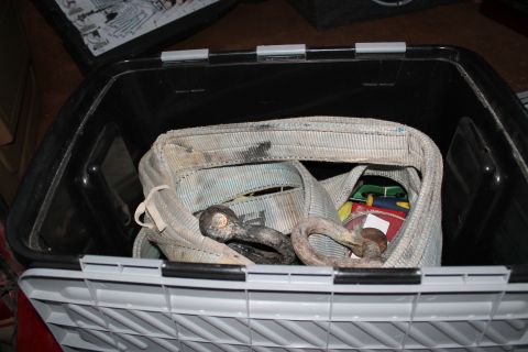1990 Ford Bronco - A close-up view of recovery gear, including straps and shackles, stored within a plastic container.