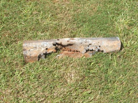1966 Ford Ranchero - A severely corroded metal pipe fragment rests on a grassy surface.