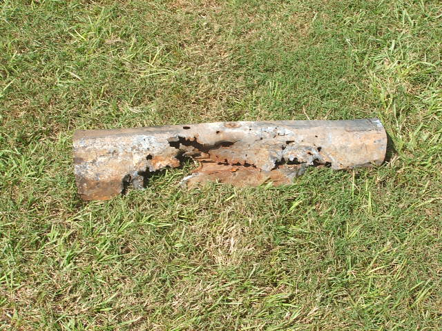 Heavily rusted metal pipe fragment lying on grass