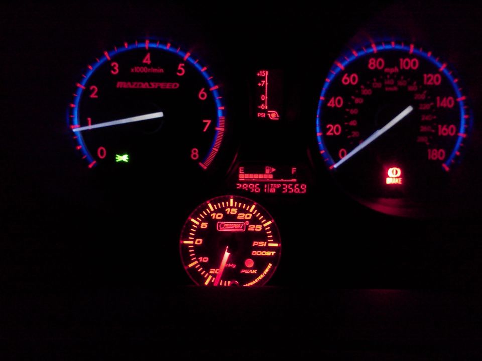 Illuminated Mazdaspeed 3 gauge cluster at night with aftermarket Prosport boost gauge below