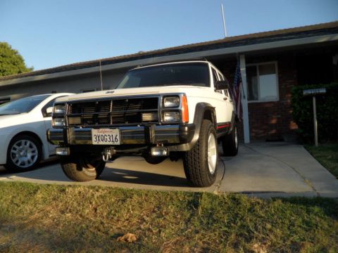 1994 Jeep Cherokee - A white Jeep Cherokee is parked in a driveway next to another car.
