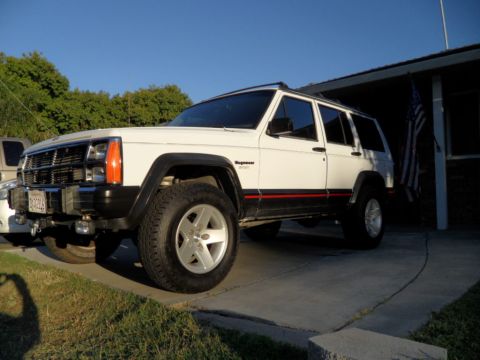 1994 Jeep Cherokee - A white 1994 Jeep Cherokee is parked in a driveway under a clear blue sky.