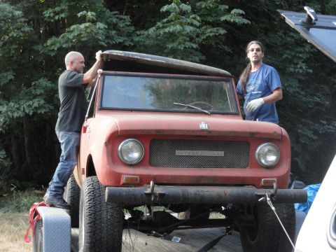 1966 International Scout 800 - A red International Scout is being loaded onto a trailer with assistance from two people.
