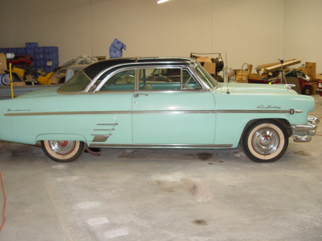 Turquoise and black 1950s Mercury hardtop coupe, side view, parked in warehouse