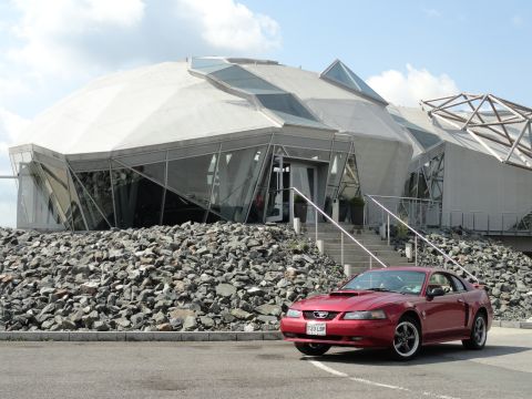 2003 Mercury Marauder - A red Ford Mustang coupe is parked outside a unique building with a geodesic dome.