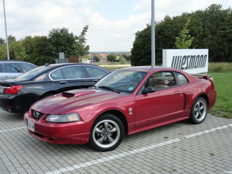 2003 Mercury Marauder - A red Ford Mustang coupe is parked in a lot next to other vehicles.