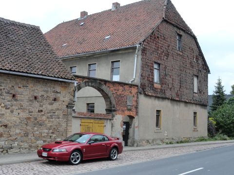2003 Mercury Marauder - A red coupe is parked on a cobblestone street in front of a historic building.