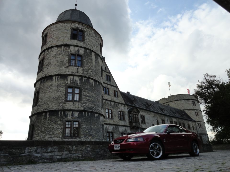 Red coupe parked in front of a castle, 2000s model year