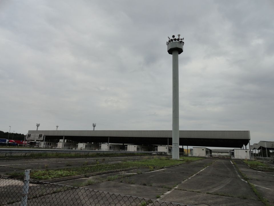 toll plaza with a tall tower topped with lights, under a cloudy sky