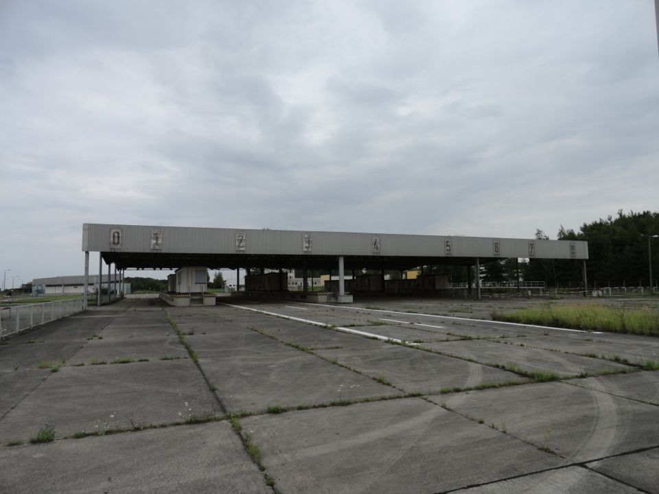 Concrete lot with a long, low building with numbered booths (0-7) under a canopy