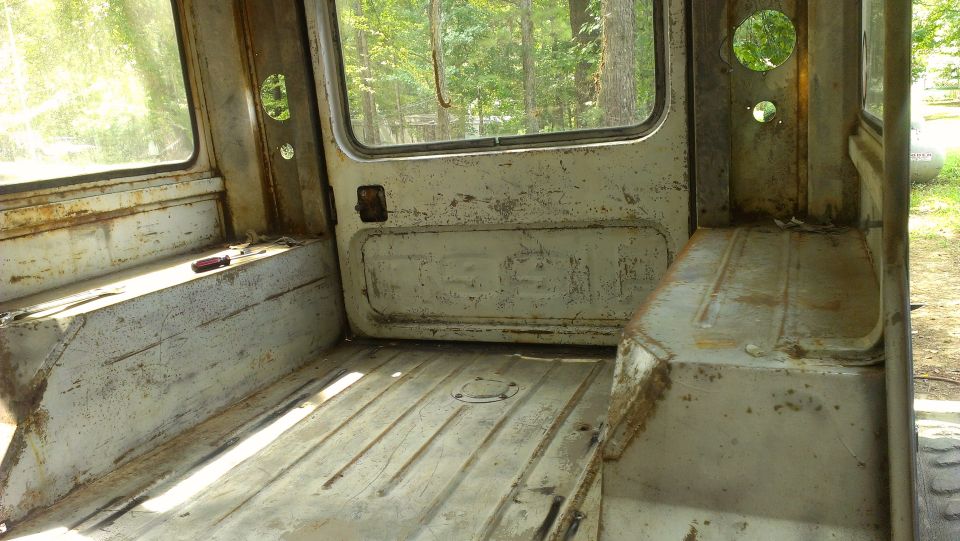 Interior view of a worn utility vehicle, showing metal floor and seats