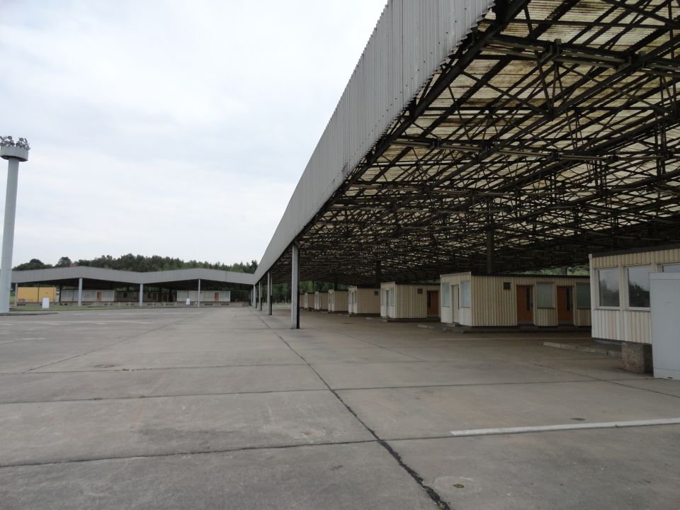 Large covered area with rows of small buildings, concrete lot, and a tall light pole
