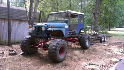 1978 Ford Bronco - This heavily modified Jeep CJ, with oversized tires and a trailer, is parked in a wooded area.