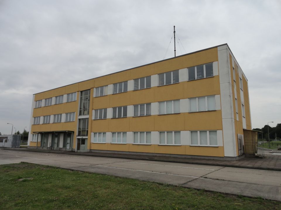 Yellow industrial building with antenna against a cloudy sky