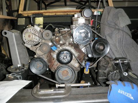 1961 International Scout 800 - Close-up of an engine assembly, showing various components and belts, with tools present.