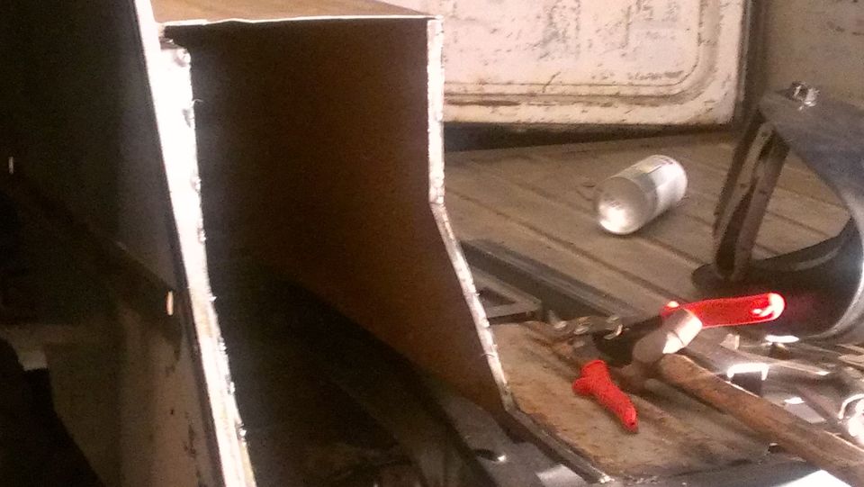 Vehicle interior with metal paneling, tools, and a can on the floor