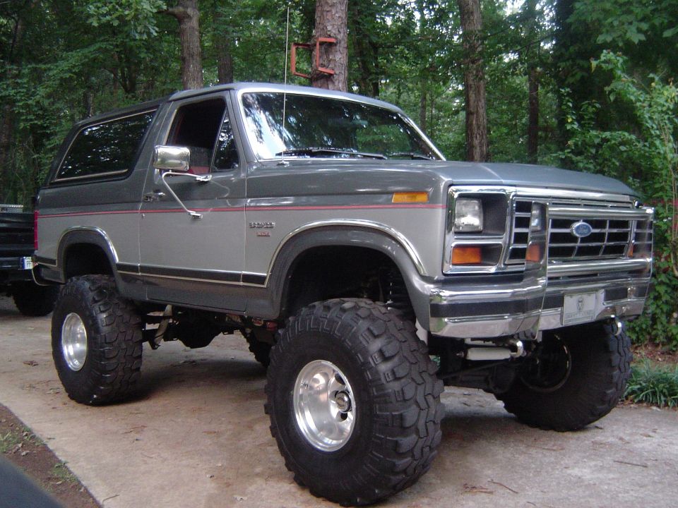 Lifted 1980s Ford Bronco, two-tone gray paint, large off-road tires, chrome wheels