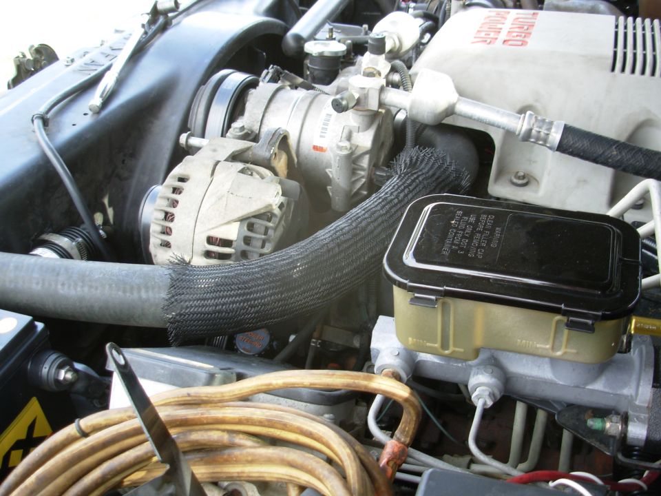 Engine bay with alternator, braided hose, and tan fluid reservoir