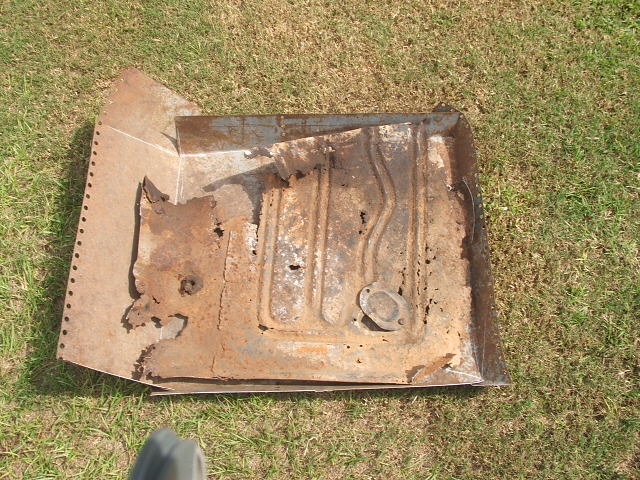 rusted floor pan section with stamped ribs and a circular flange