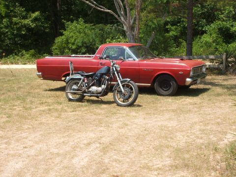 1966 Ford Ranchero - A red 1966 Ford Ranchero pickup truck is parked next to a motorcycle in a grassy outdoor setting.