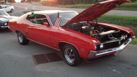 2007 Ford Mustang - Red classic car with hood open, parked outdoors with an American flag on the fender.