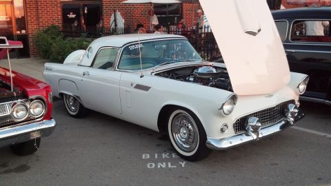 2007 Ford Mustang - A white 1955 Ford Thunderbird is parked with its hood open, next to another classic car.