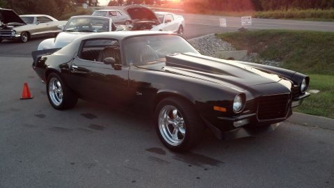 2007 Ford Mustang - Black 1970s Chevrolet Camaro parked outdoors with other vehicles in the background.