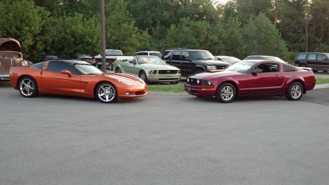 2007 Ford Mustang - Two sports cars and several other vehicles are parked in an outdoor lot.