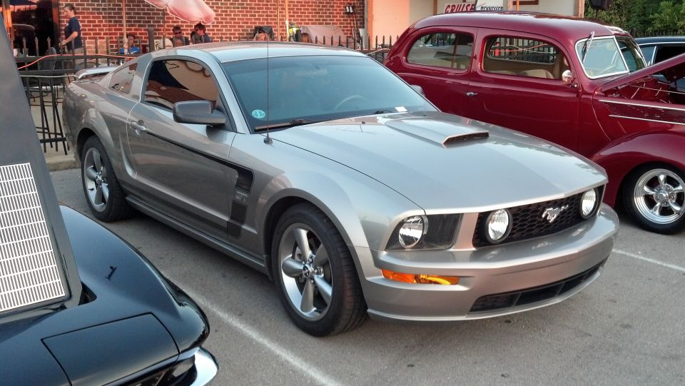 Silver 2007 Ford Mustang parked next to a red classic car