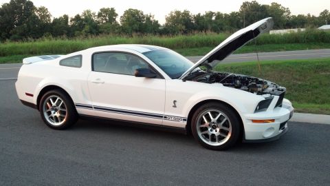 2007 Ford Mustang - 2007 Ford Mustang GT500 with hood open, showing engine and side stripes.