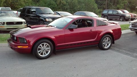 2007 Ford Mustang - A red Ford Mustang coupe is parked in a lot with other vehicles visible in the background.