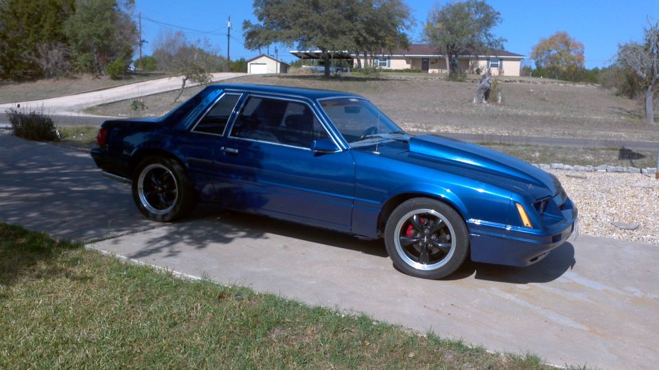 Blue coupe car with a hood scoop parked on a driveway