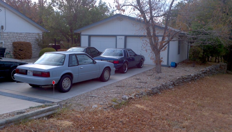 Light blue coupe parked in driveway, rear quarter view