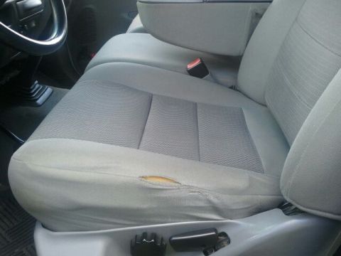 2004 Ford F-350 - The driver's seat shows significant wear and tear, with a large rip on the side bolster.