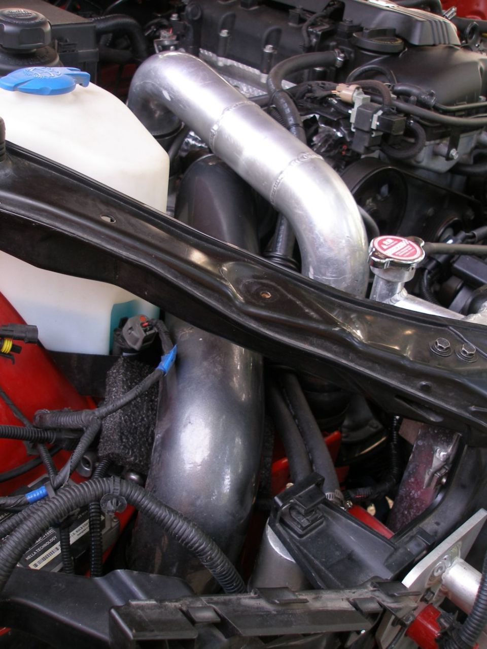 Engine bay with large diameter aluminum intake piping and coolant reservoir