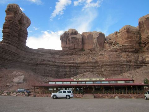 1991 Ford LTD Crown Victoria - A white SUV and a dark sedan are parked in front of a building with large red rock formations in the background.