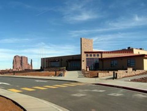 1991 Ford LTD Crown Victoria - A view of Monument Valley, a large rock formation and a contemporary building under a clear blue sky.